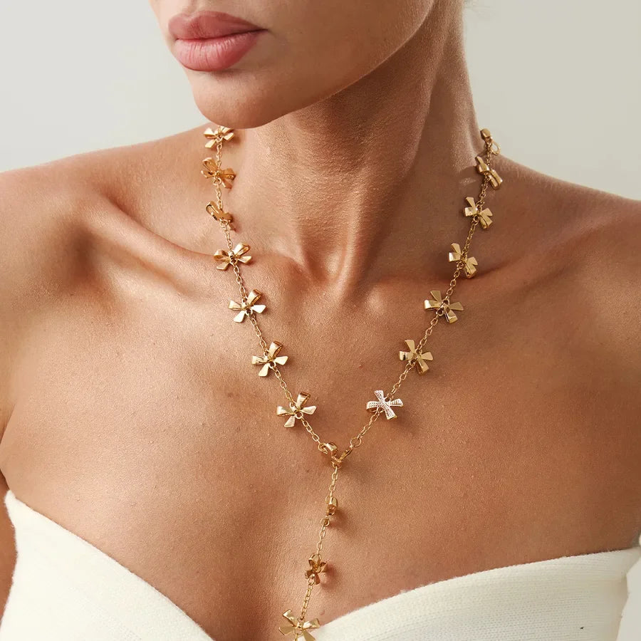 Woman wearing gold floral necklace from Moment Jewels, elegant jewelry on bare neckline