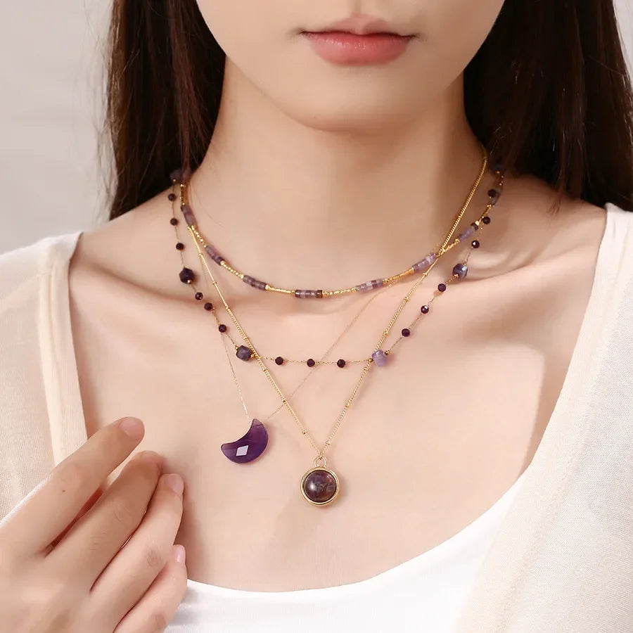 Model wearing layered purple gemstone necklaces by Moment Jewels, close-up view